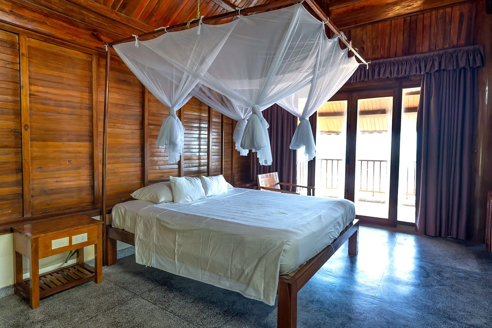 Elegant wooden cabin bedroom with canopy bed and natural lighting.