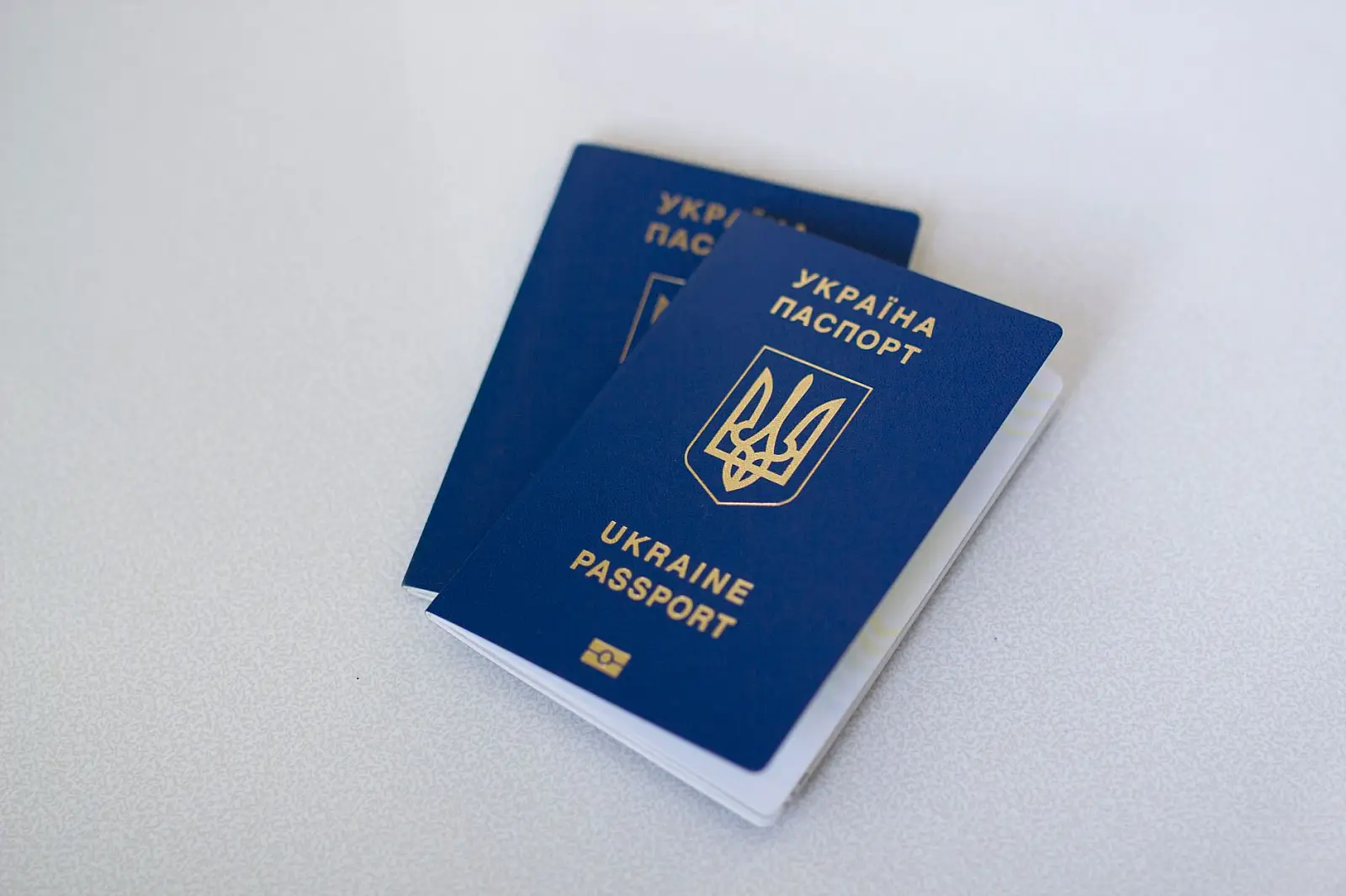 Blue Ukrainian passports on a light surface, highlighting travel documents.